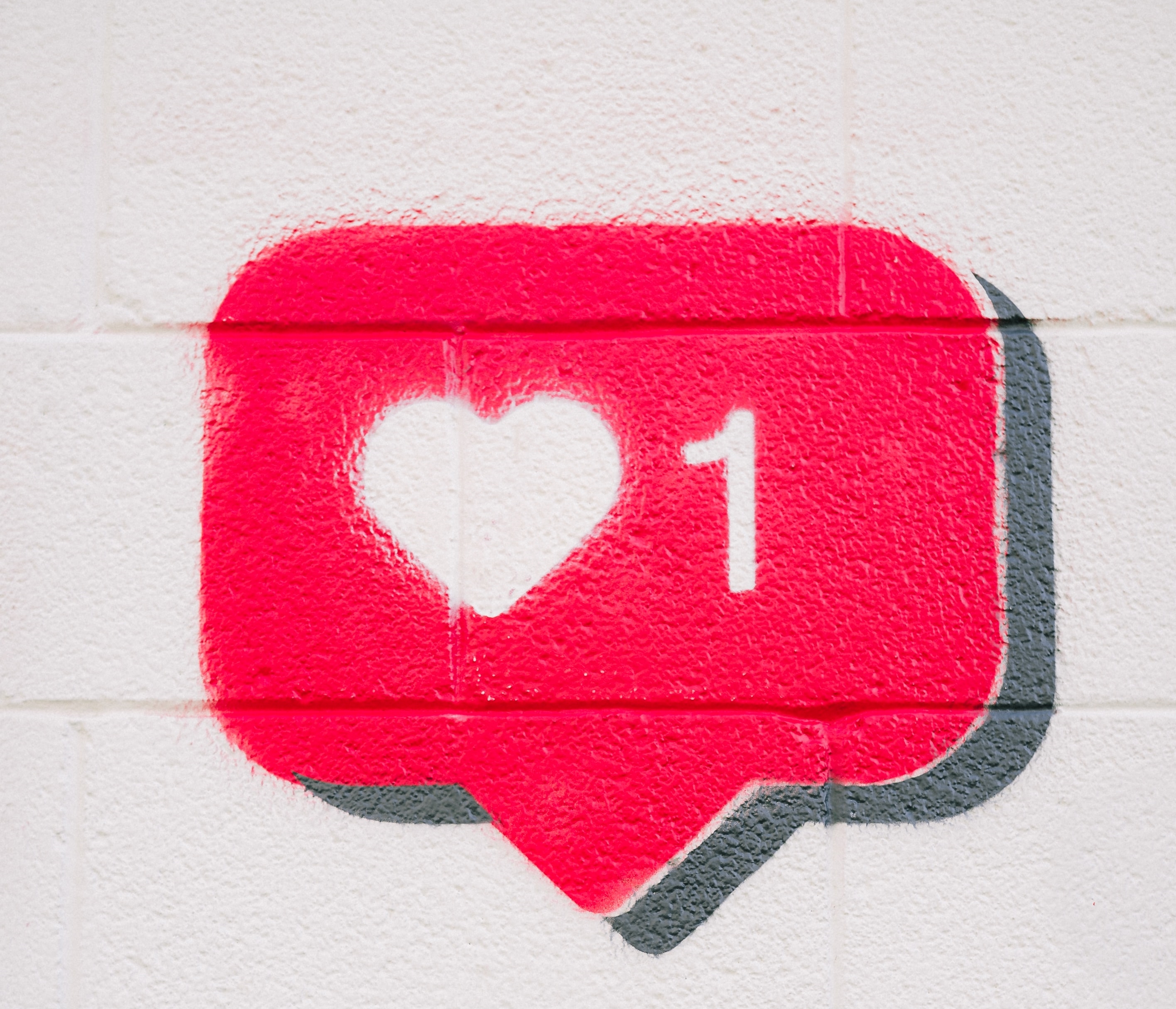 Bildliche Darstellung eines Symbols eines sogenannten Likes durch eine rote Sprechblase mit einem weißen Herzchen und einer weißen Eins drauf.